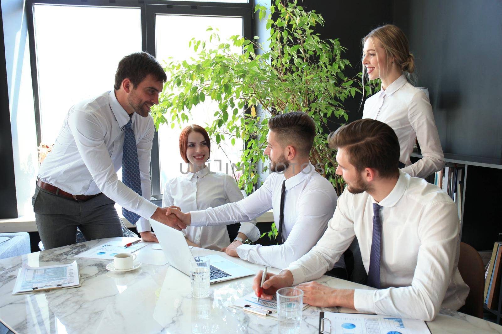 Businessman shaking hands to seal a deal with his partner and colleagues in office. by tsyhun