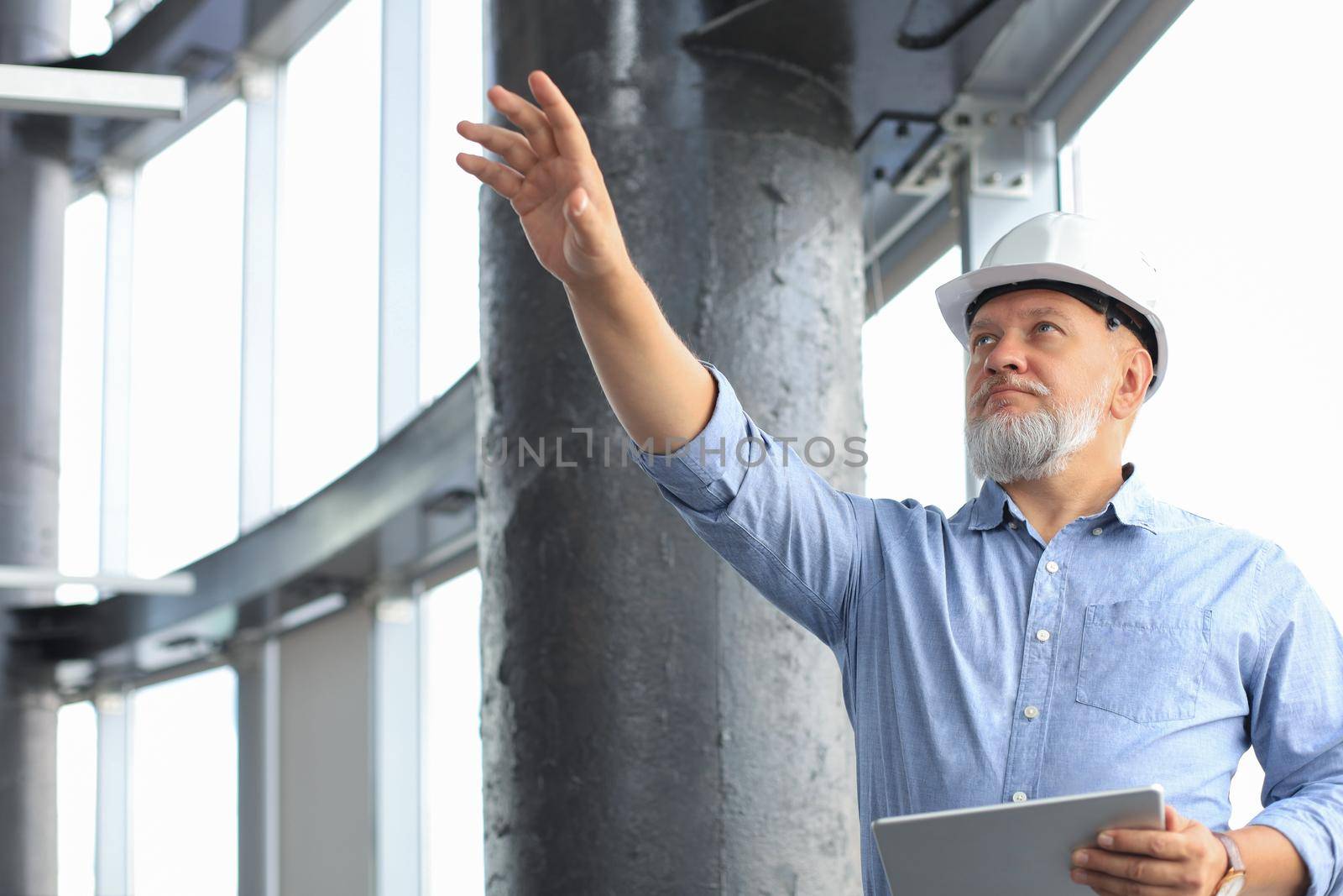 Mature architect wearing hardhat inspecting new building
