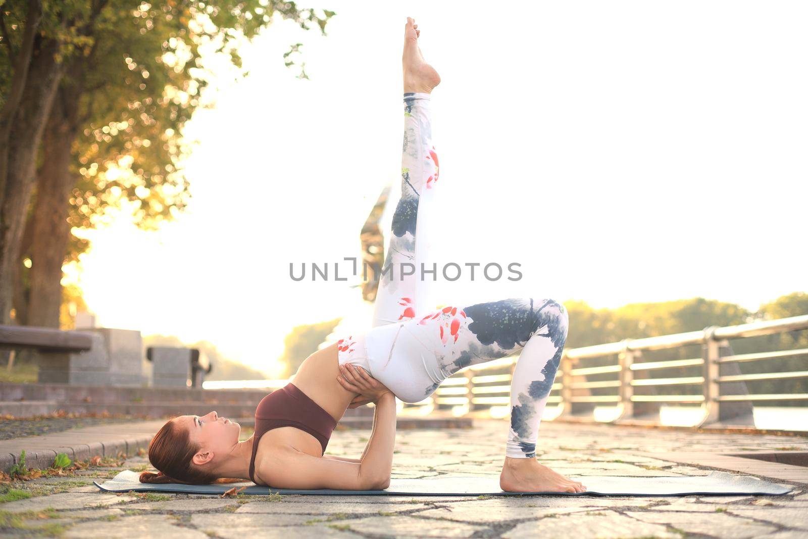 Concentrated pretty strong young redhead sports woman make yoga exercise outdoors