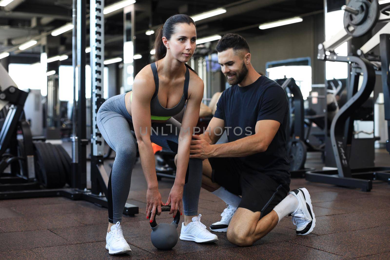 Fitness instructor exercising with his client at the gym