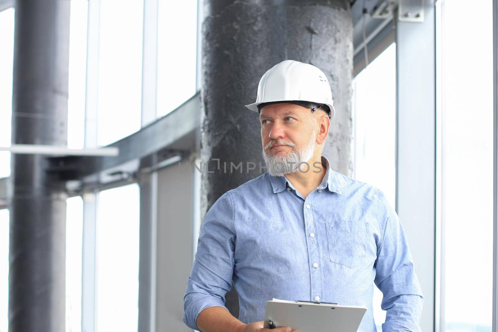 Mature architect wearing hardhat inspecting new building