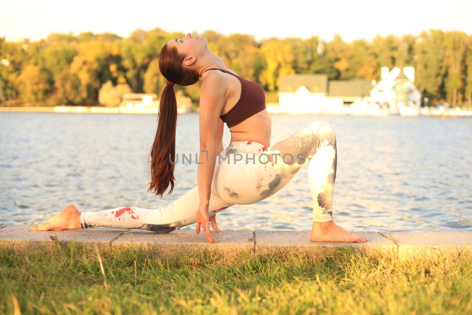 Young redhead sports woman make stretching yoga exercise outdoors. by tsyhun