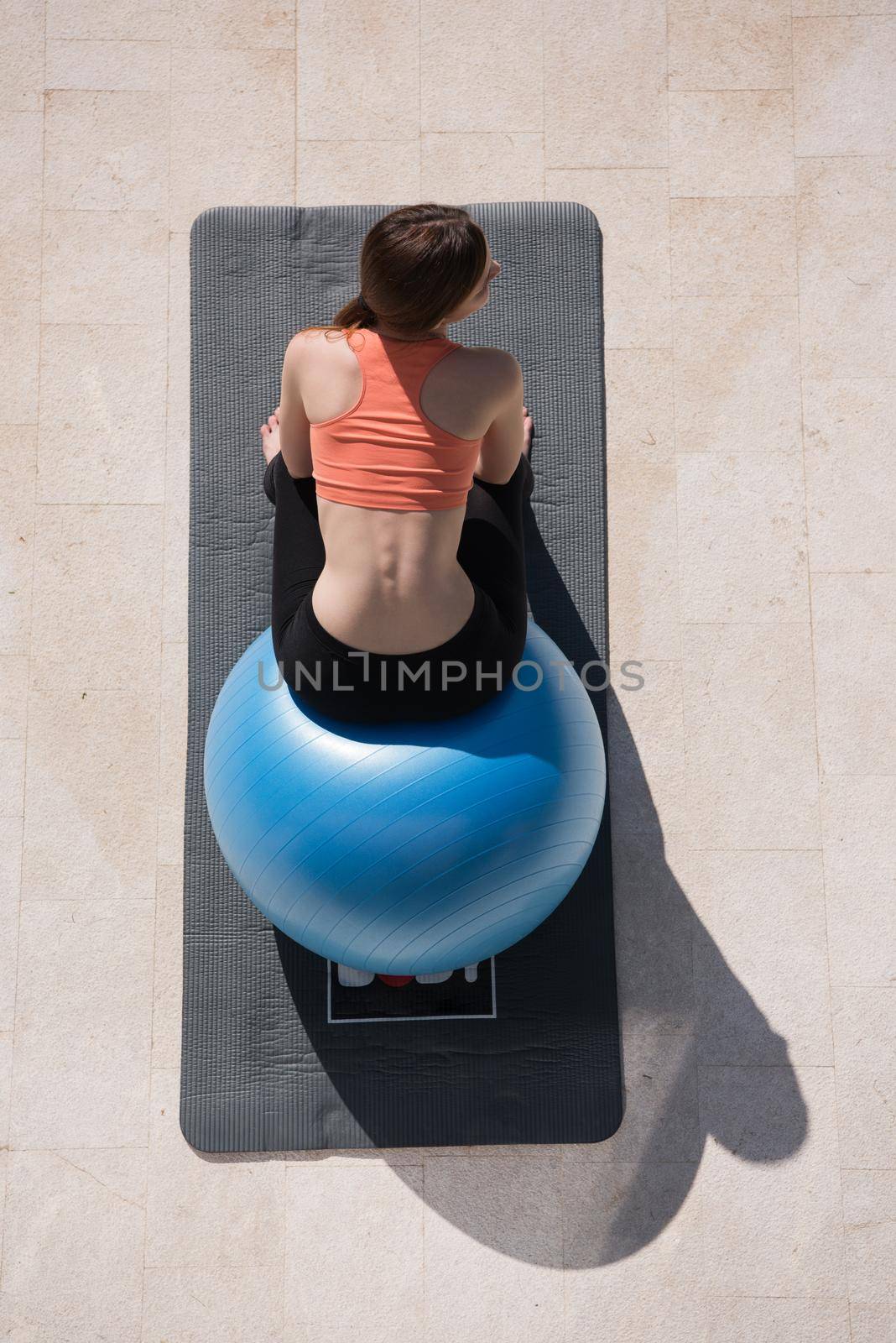 young beautiful woman doing exercise with pilates ball in front of her luxury home villa top view