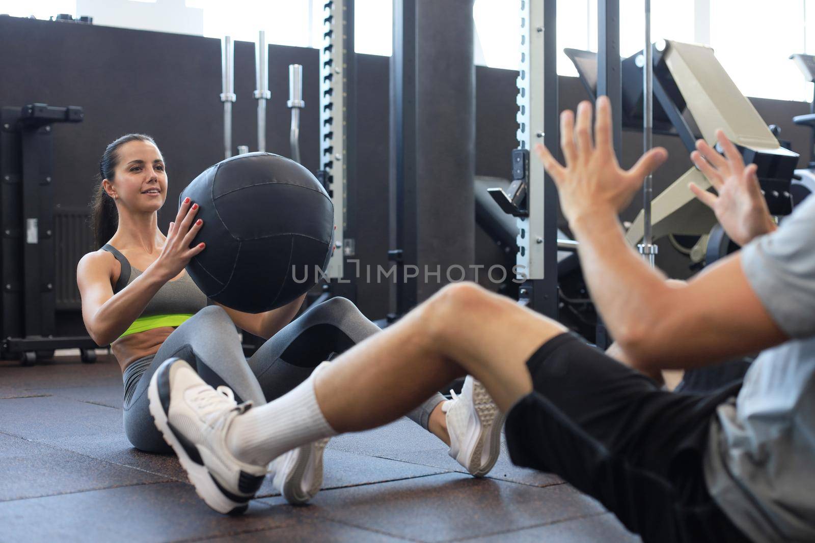 Fit and muscular couple exercising with medicine ball at gym. by tsyhun