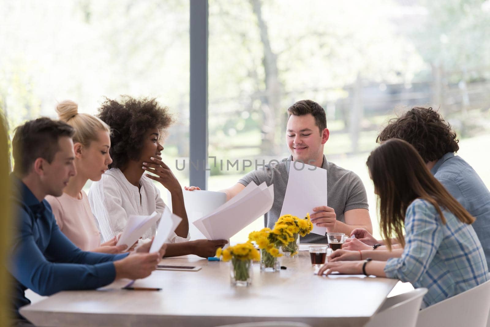 Multiethnic startup business team on meeting in modern bright office interior brainstorming, working on laptop and tablet computer