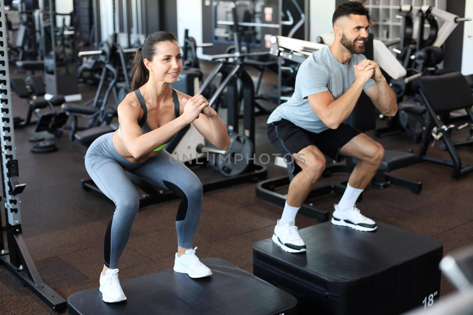 Fit couple doing jumping squats in crossfit gym. by tsyhun