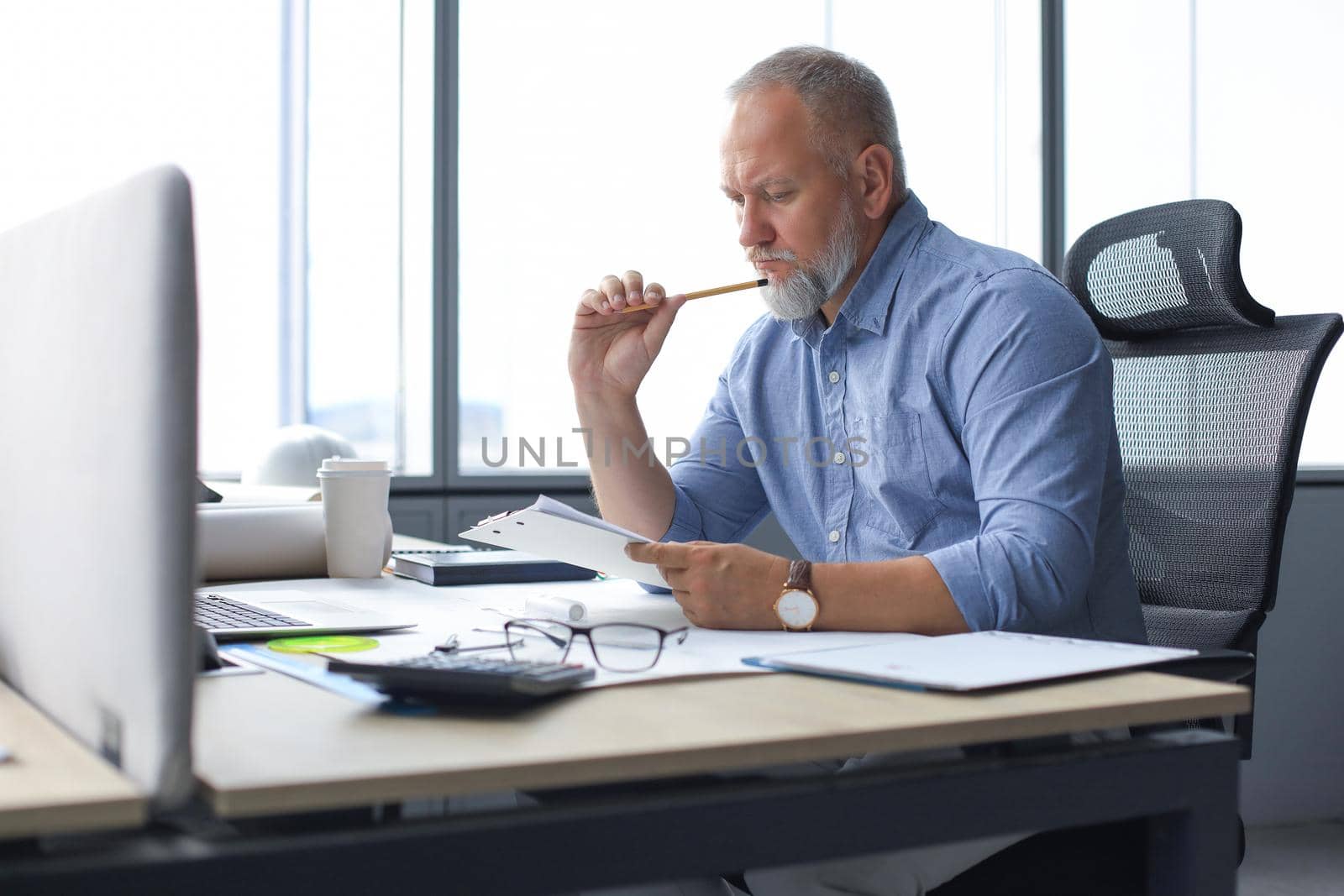 Good looking mature architect drawing something while working in the office