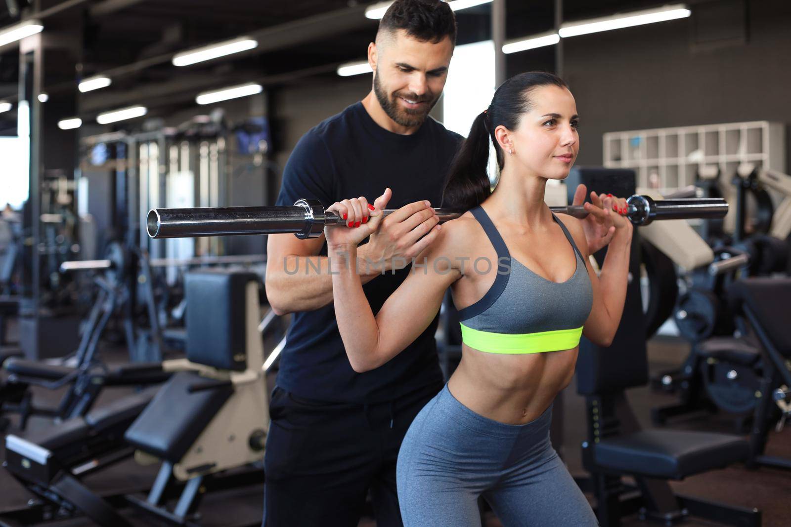 Man and woman with barbell flexing muscles in gym