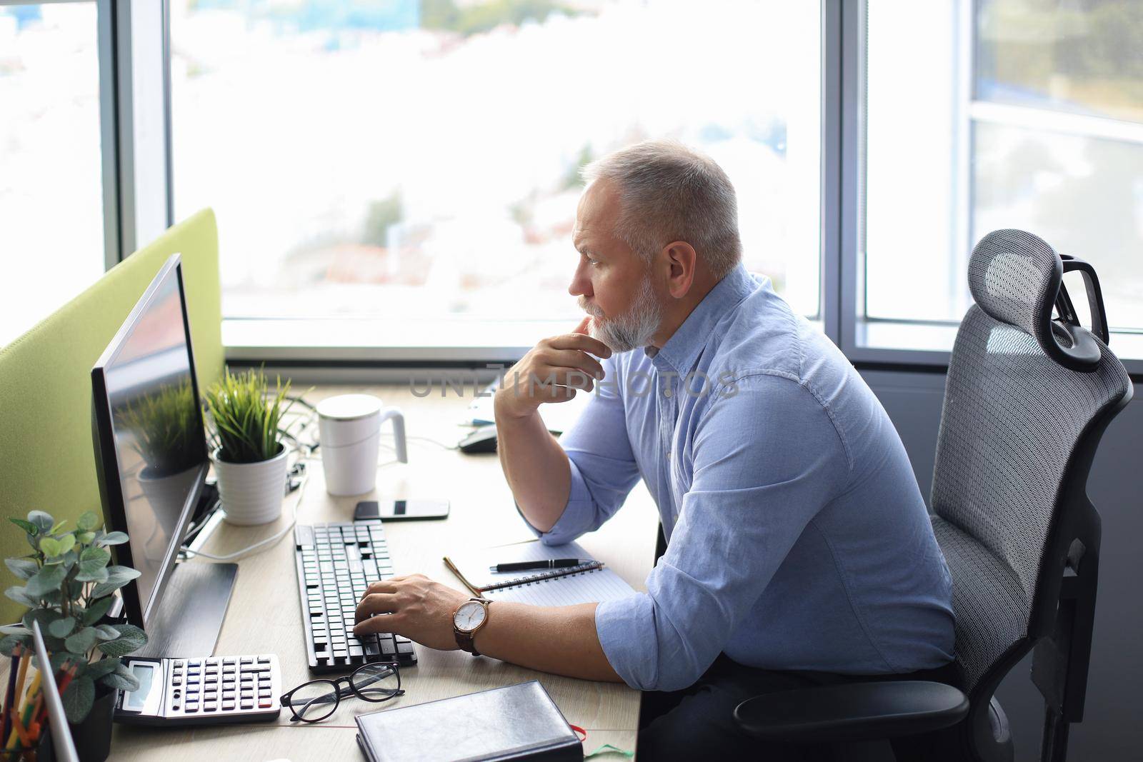 Focused mature businessman deep in thought while sitting at a table in modern office