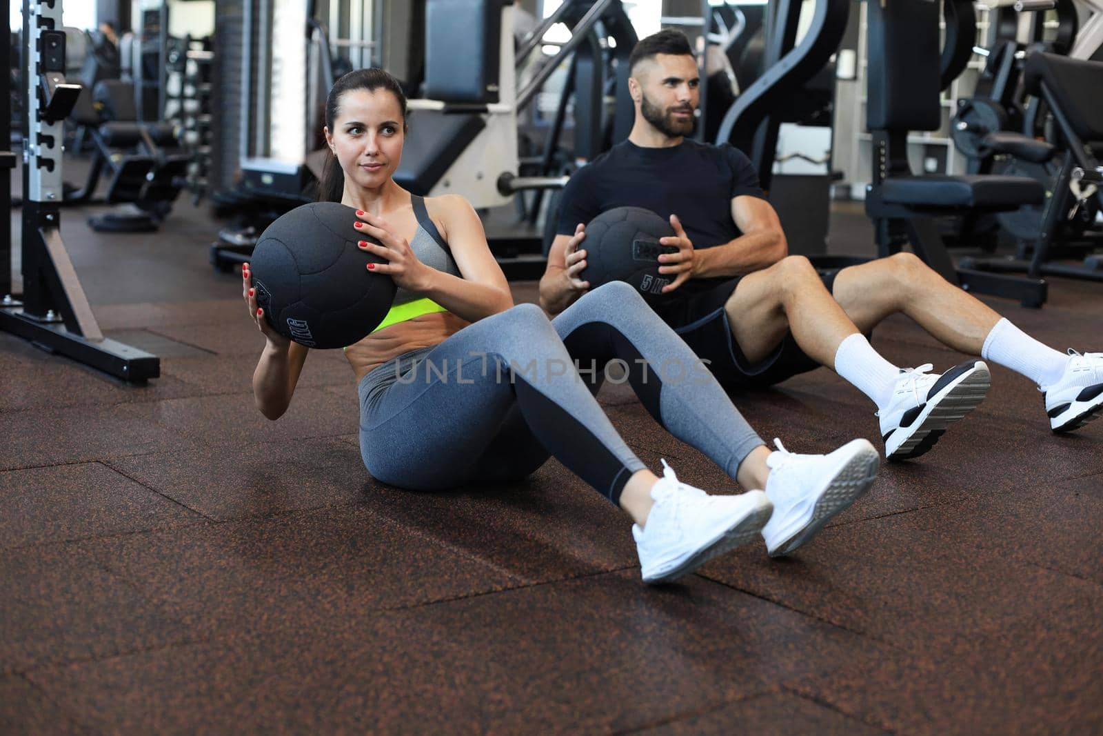 Beautiful young sports couple is working out with medicine ball in gym