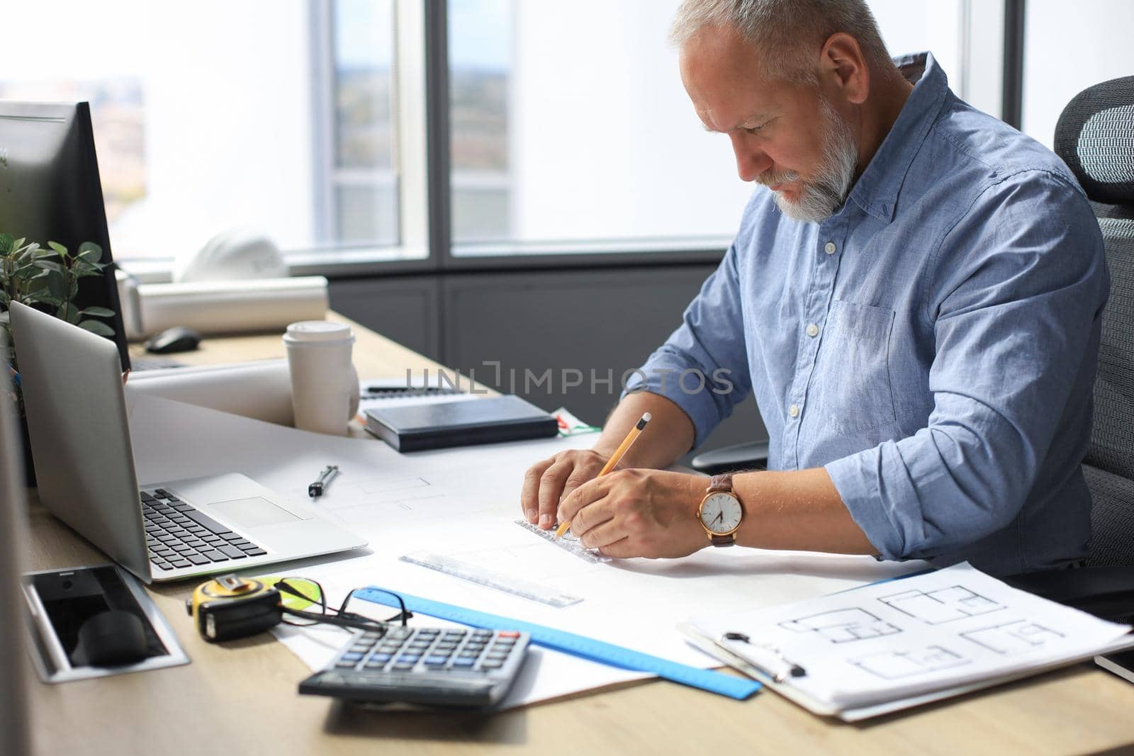 Good looking mature architect drawing something while working in the office