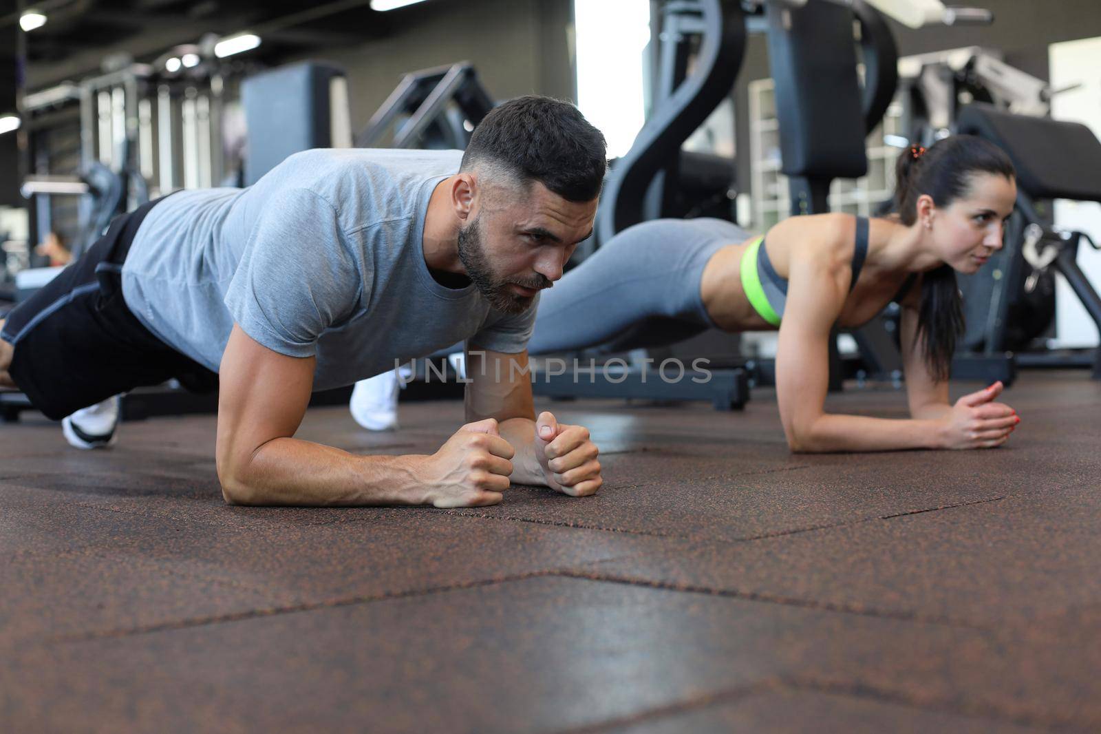 Portrait of beautiful young sports couple on a plank position. by tsyhun