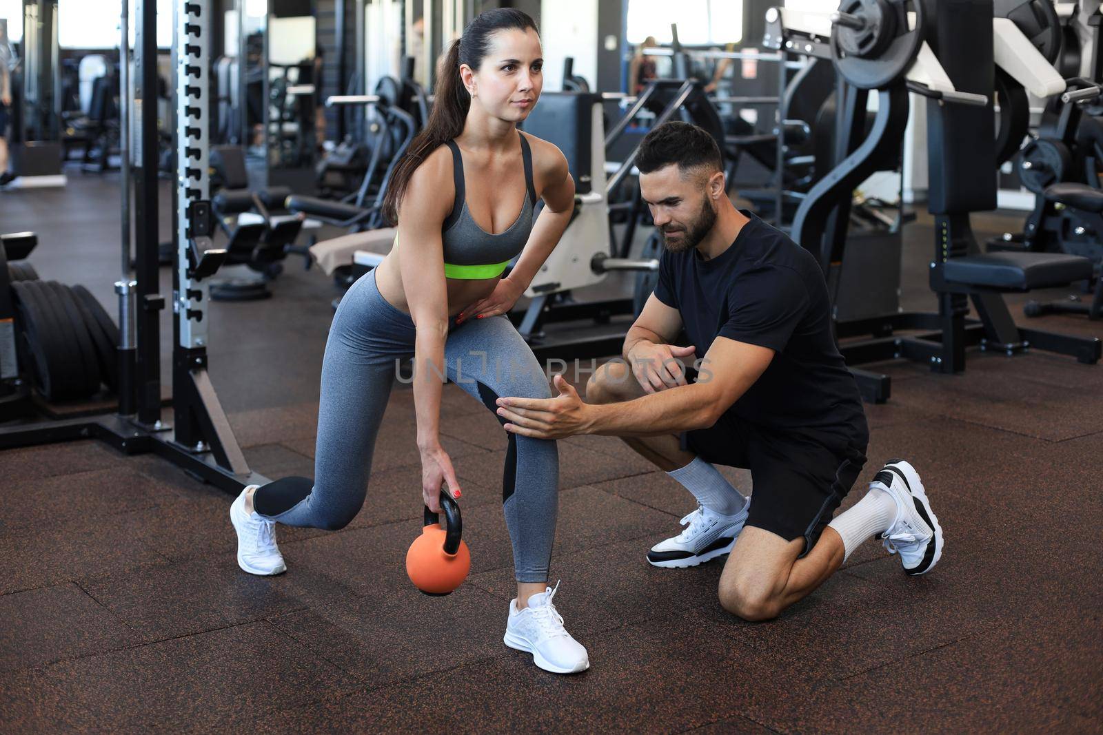 Fitness instructor exercising with his client at the gym