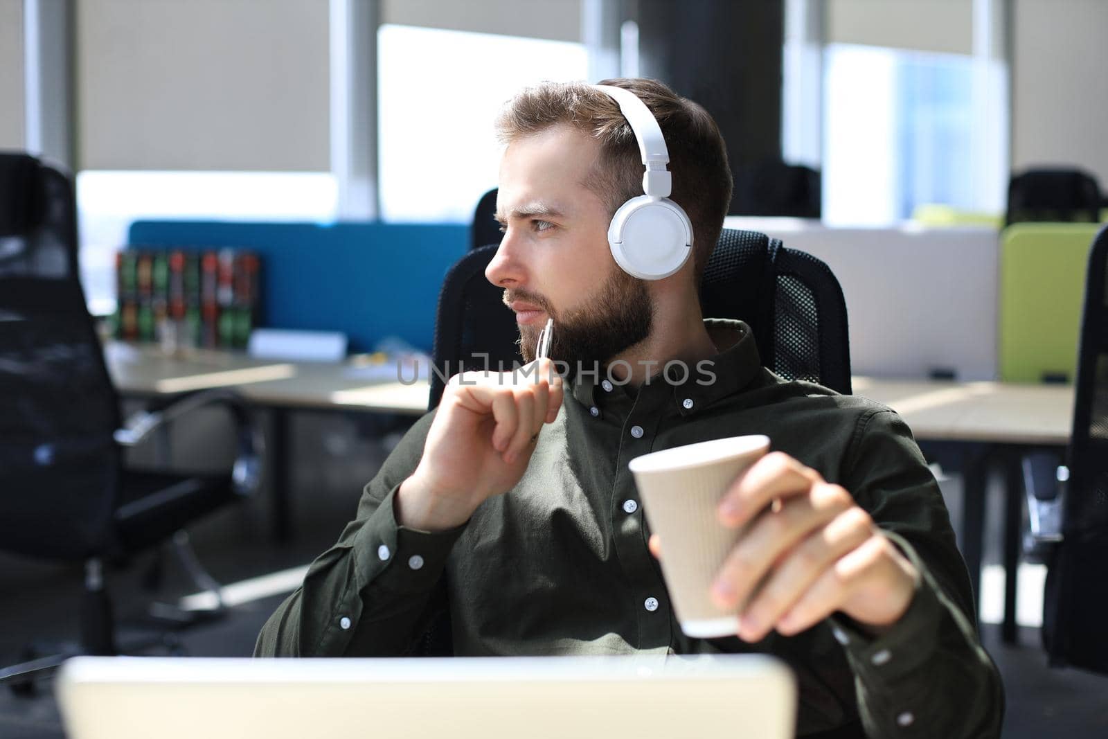 Young modern business man sitting in the office and holding paper cup