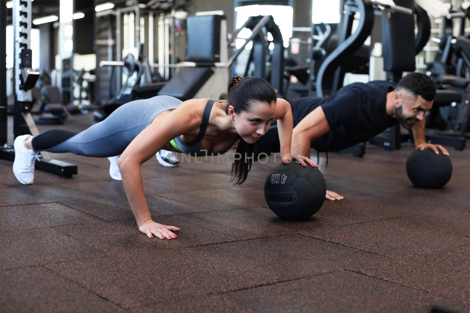 Beautiful young sports couple is working out with medicine ball in gym