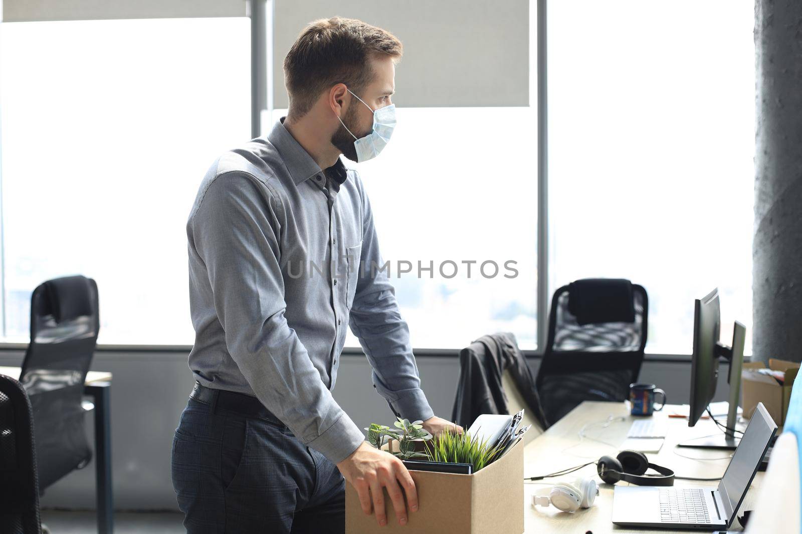 Dismissal employee in an epidemic coronavirus covid-19. Sad dismissed worker are taking his office supplies with him from office