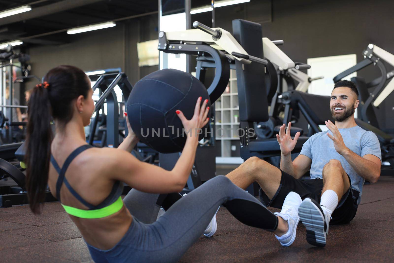 Fit and muscular couple exercising with medicine ball at gym