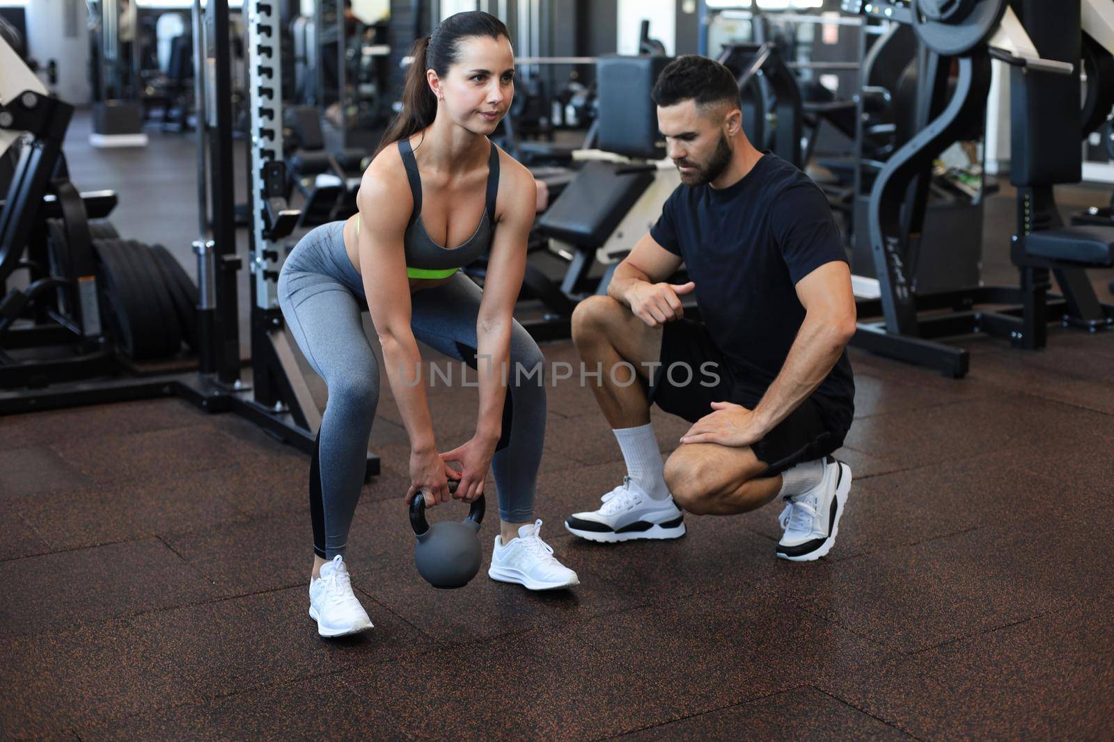 Fitness instructor exercising with his client at the gym. by tsyhun