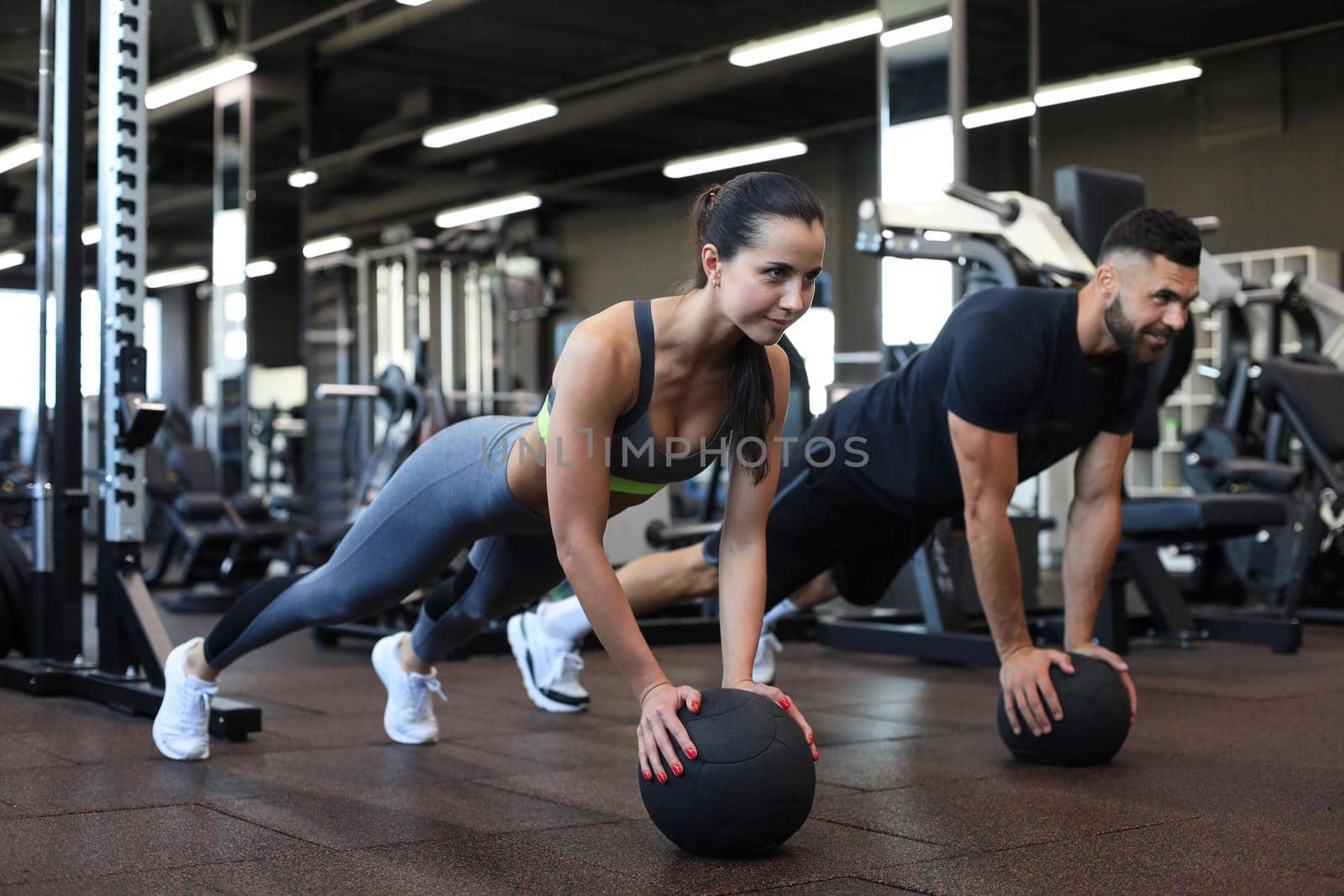 Beautiful young sports couple is working out with medicine ball in gym. by tsyhun