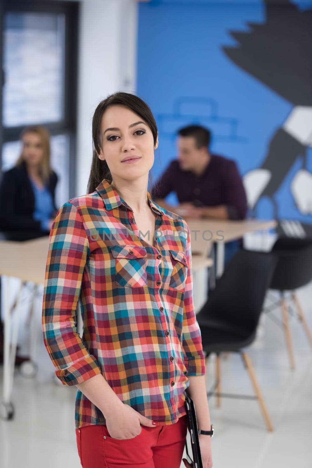 portrait of young business woman at office with team in background by dotshock