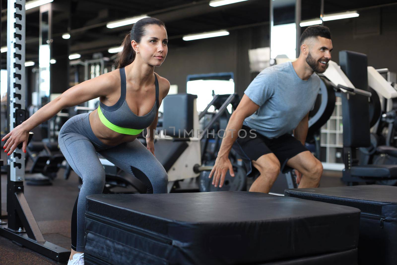 Fit couple doing jumping squats in crossfit gym