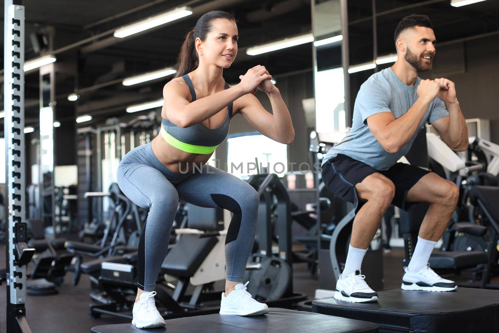 Fit couple doing jumping squats in crossfit gym