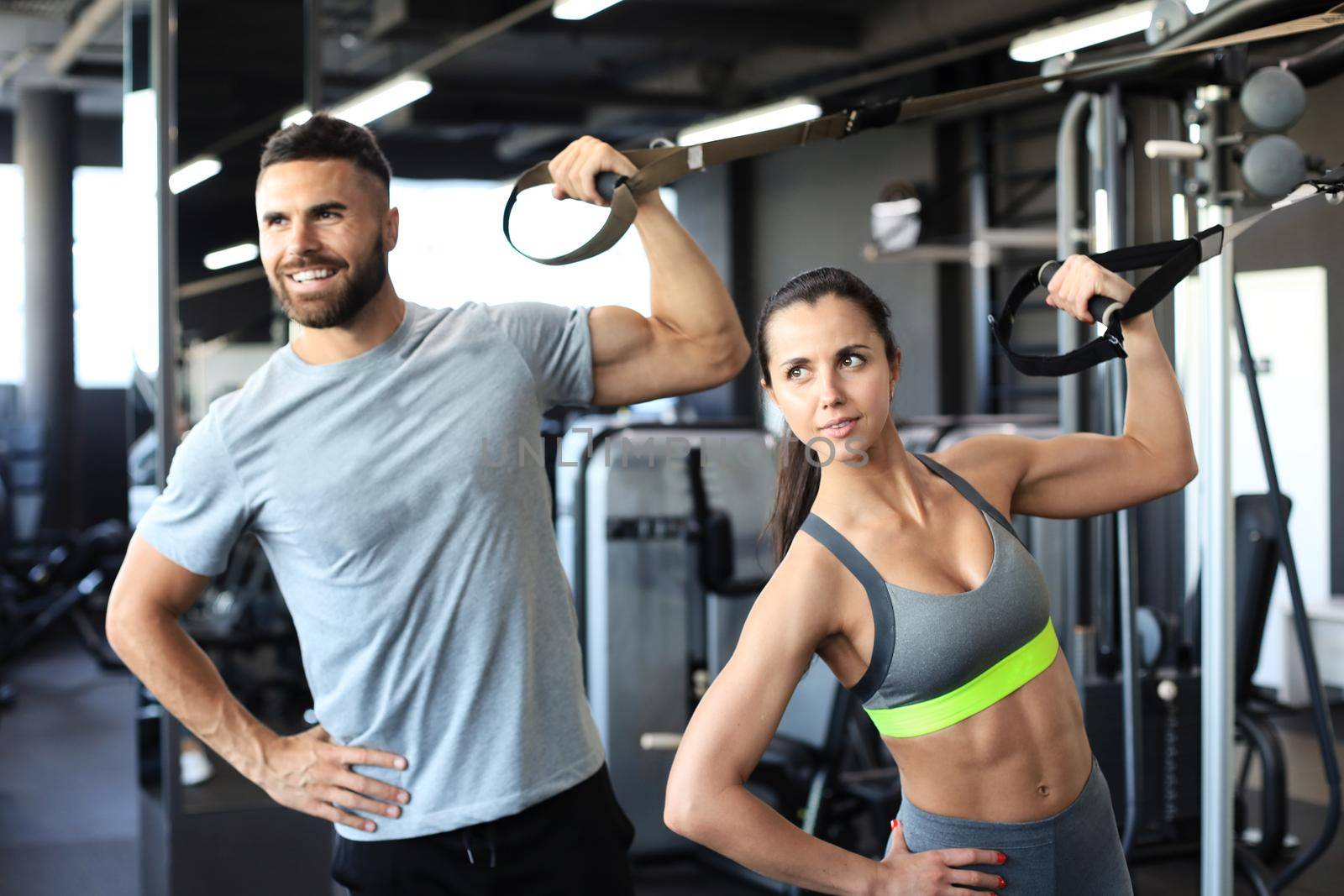 Young couple on body training with trx in gym