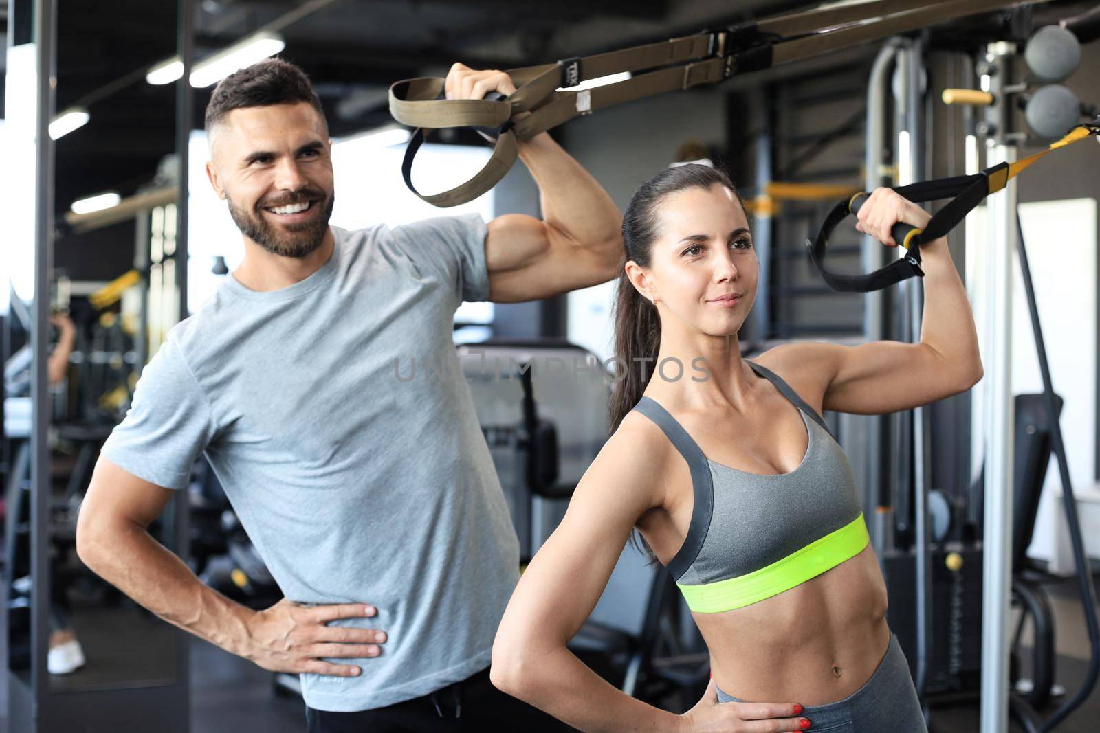 Young couple on body training with trx in gym