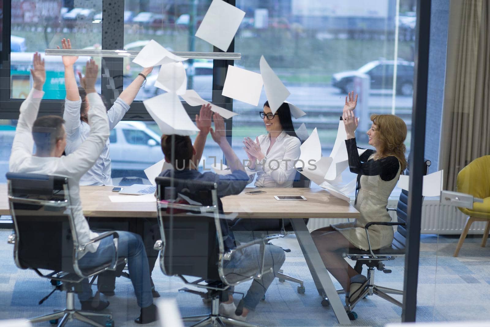 Group of young business people throwing documents and looking happy while celebrating success at their working places in startup office