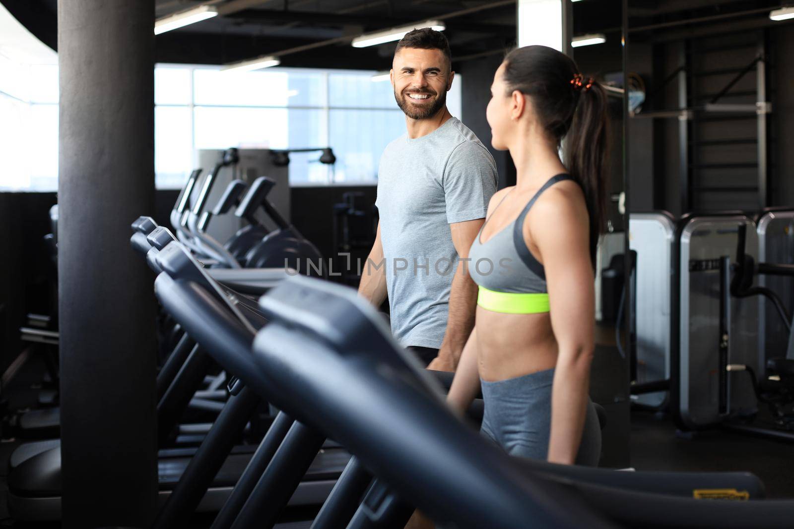 Attractive people on the treadmill at sport gym. by tsyhun