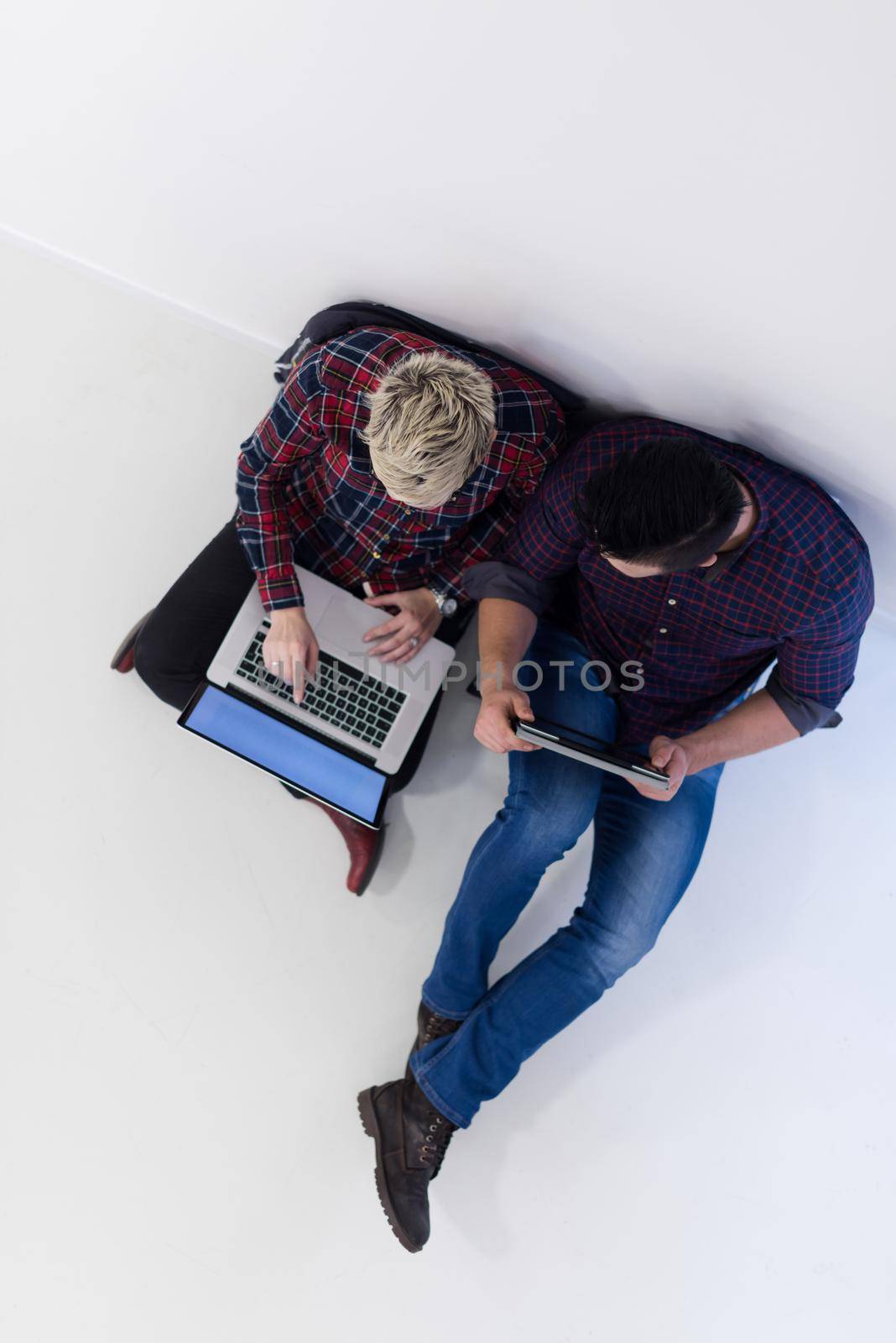 startup business and new mobile technology concept with  young couple in modern bright office interior working on laptop and tablet computer on new creative project and brainstorming, aerial top view