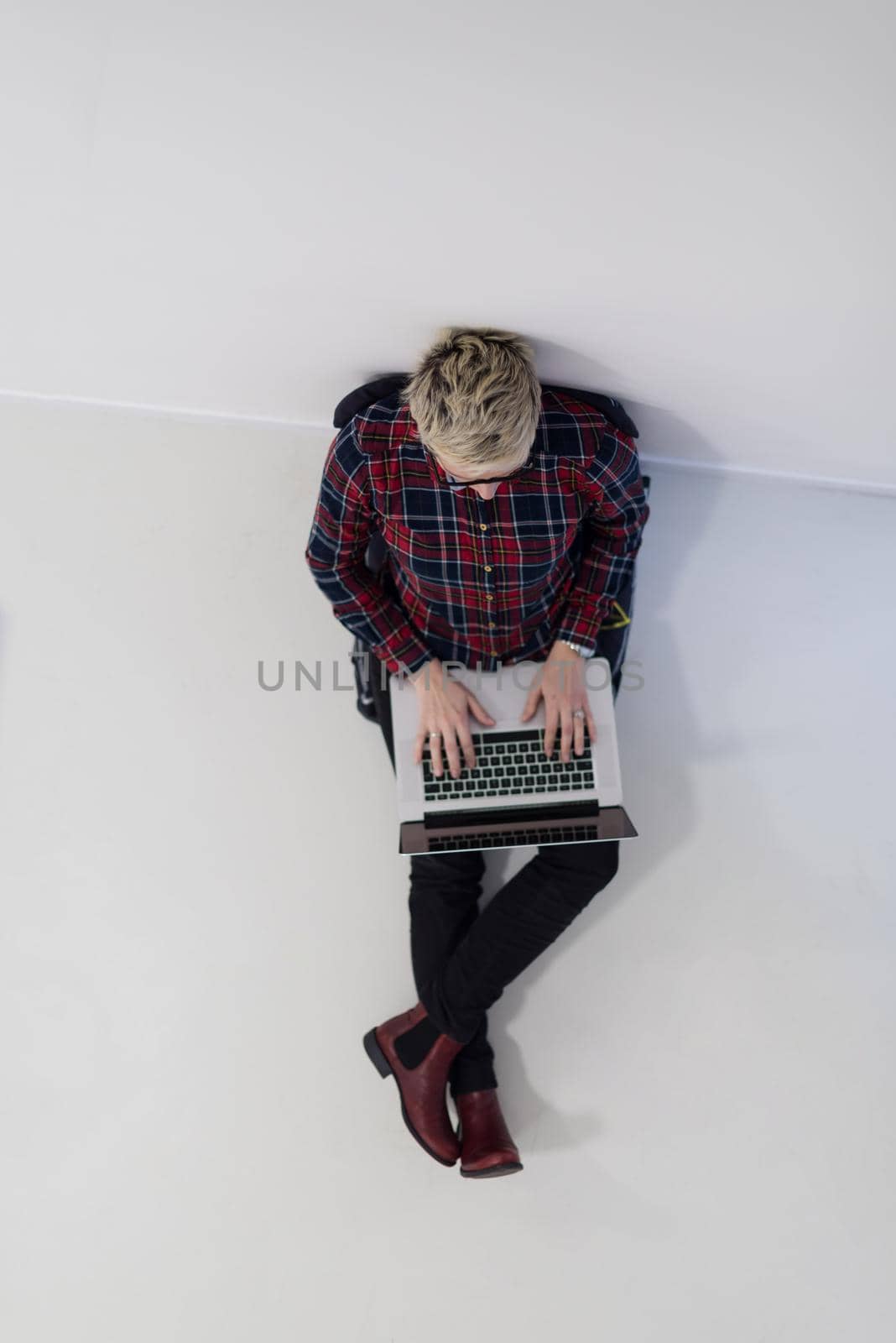 top view of young business woman working on laptop computer in modern bright startup office interior, sitting on floor