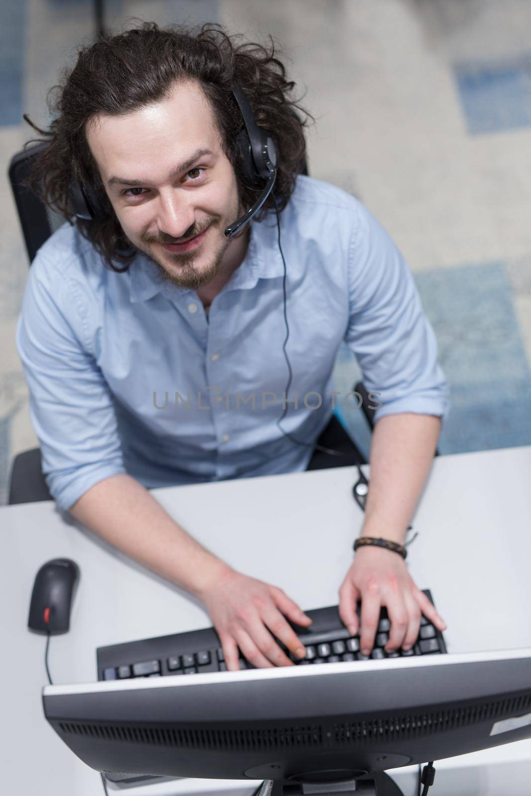 top view of a young smiling male call centre operator doing his job with a headset