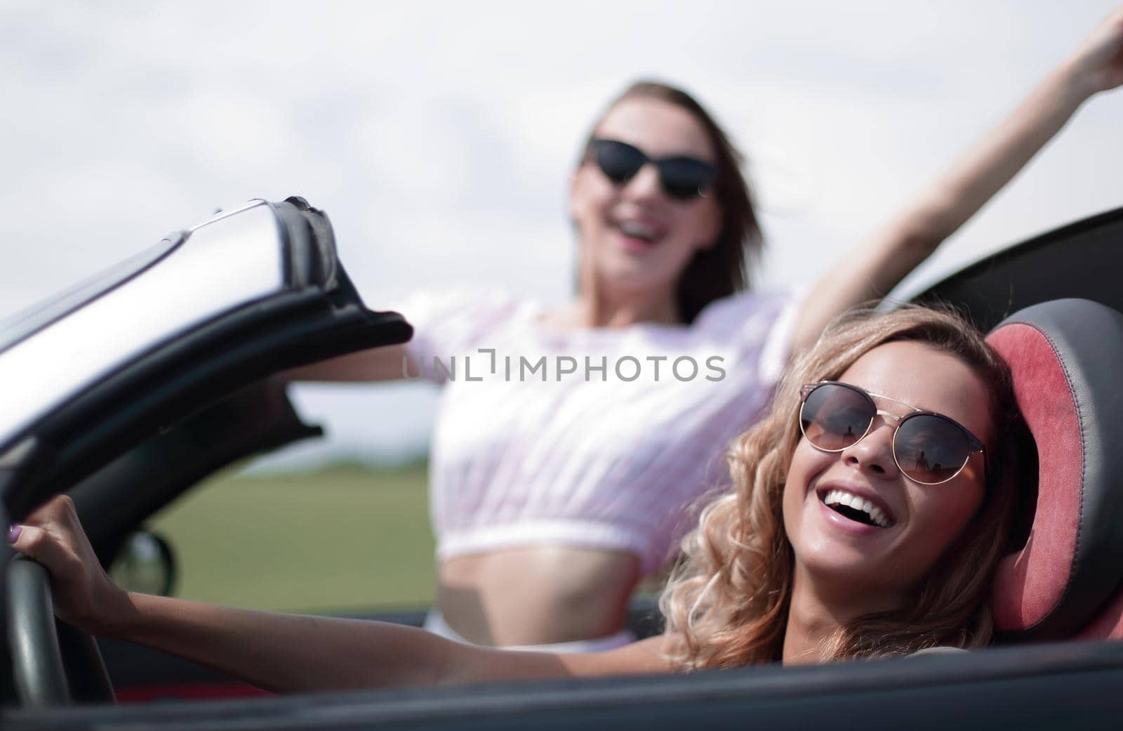 close up.two happy young women in a convertible car . fashionable lifestyle