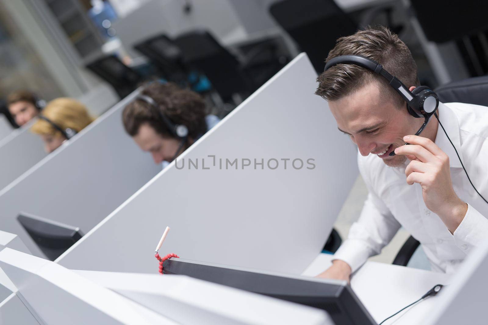 young smiling male call centre operator doing his job with a headset