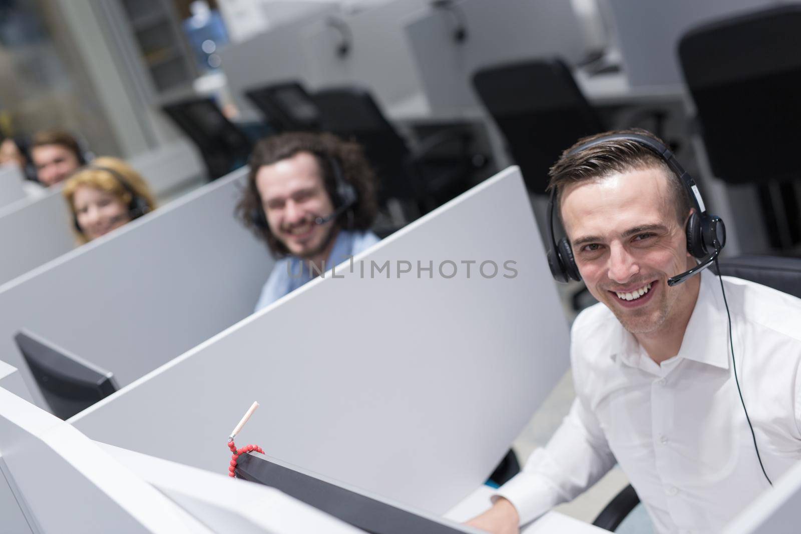 young smiling male call centre operator doing his job with a headset