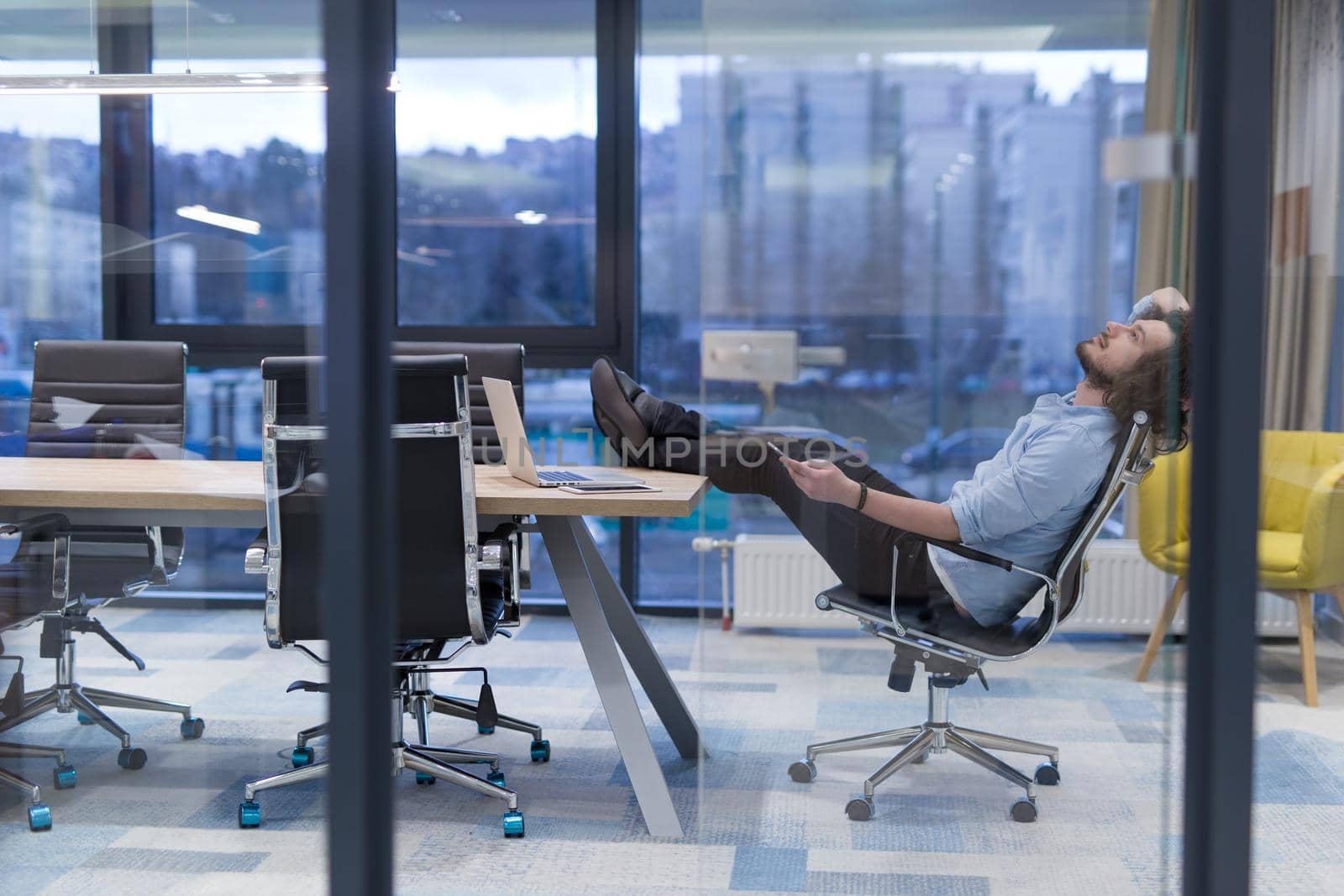 A time for relax. Young tired casual businessman relaxing at the desk in his office