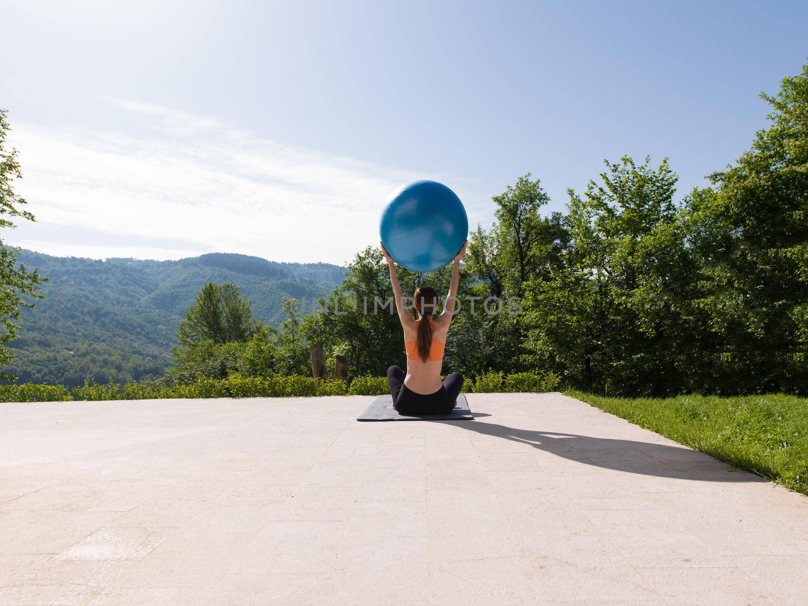 young beautiful woman doing exercise with pilates ball in front of her luxury home villa