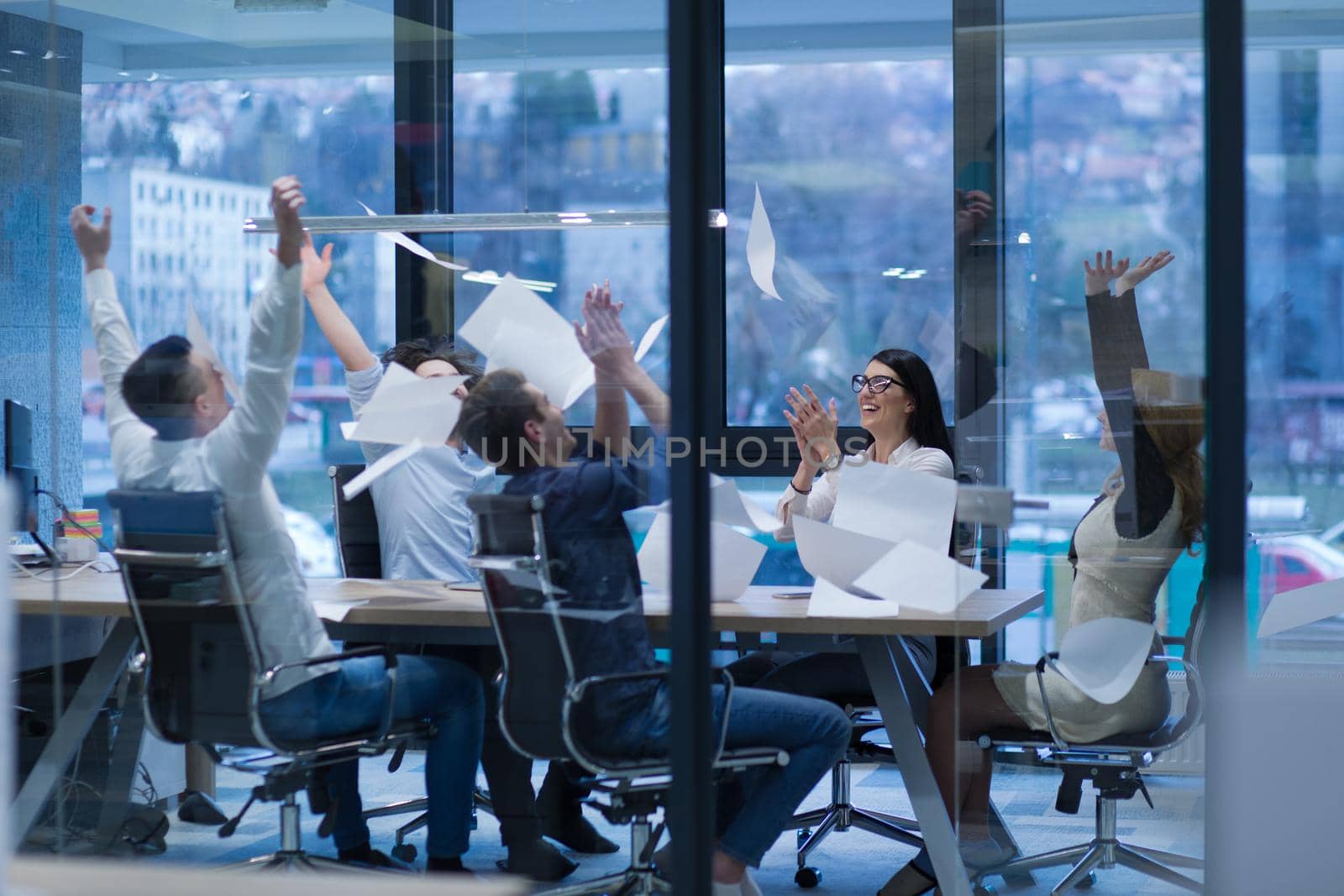 Group of young business people throwing documents and looking happy while celebrating success at their working places in startup office