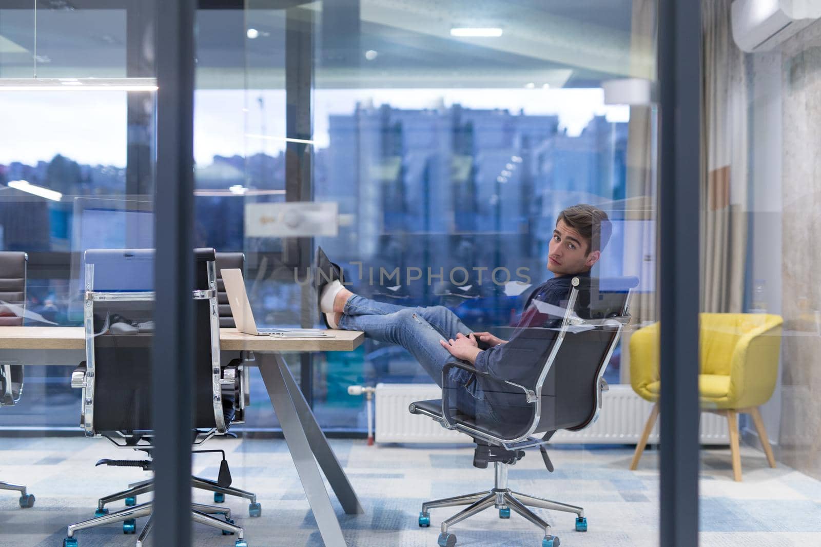 A time for relax. Young tired casual businessman relaxing at the desk in his office