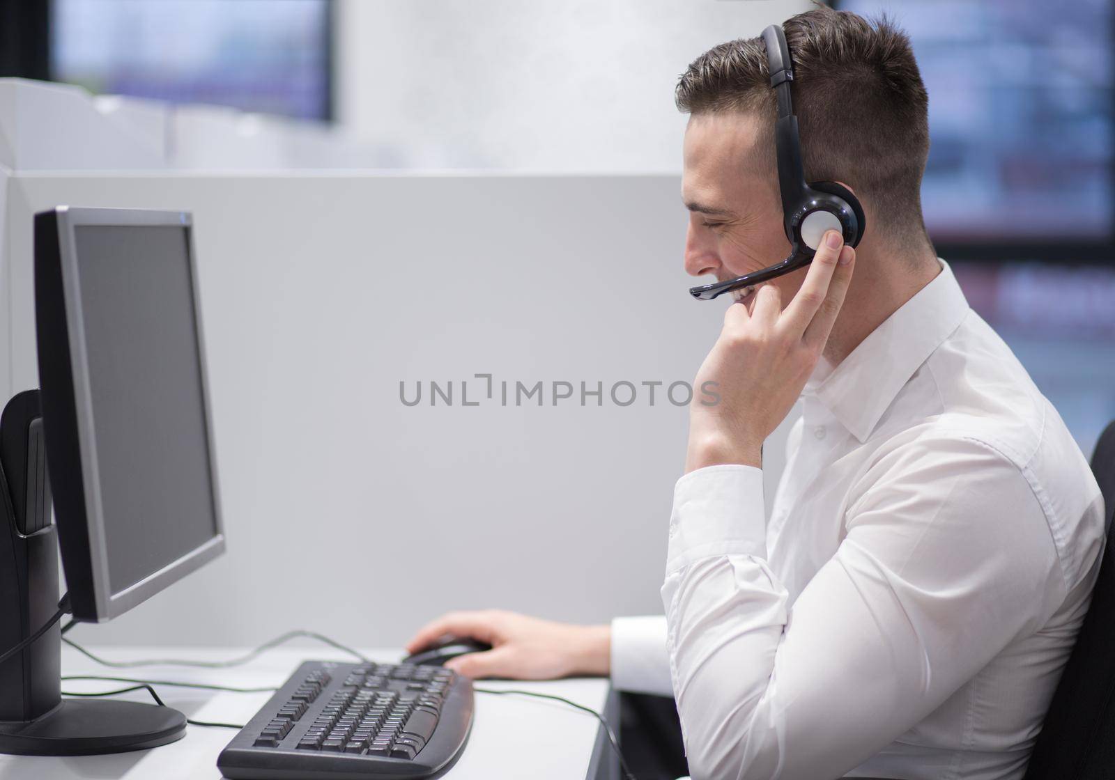 young smiling male call centre operator doing his job with a headset