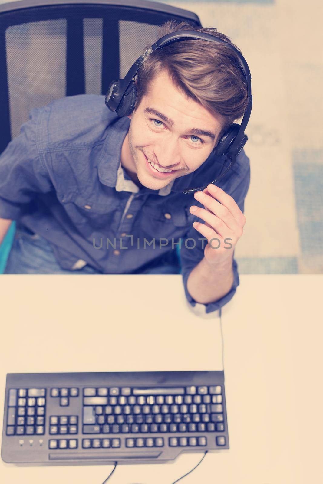 top view of a young smiling male call centre operator doing his job with a headset