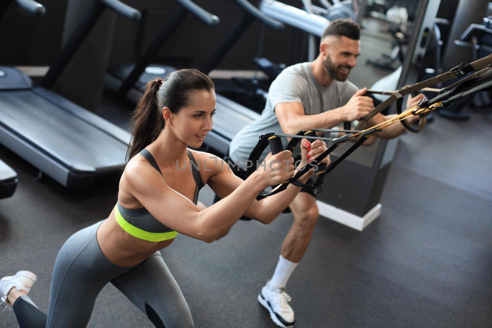 Young couple on body training with trx in gym. by tsyhun
