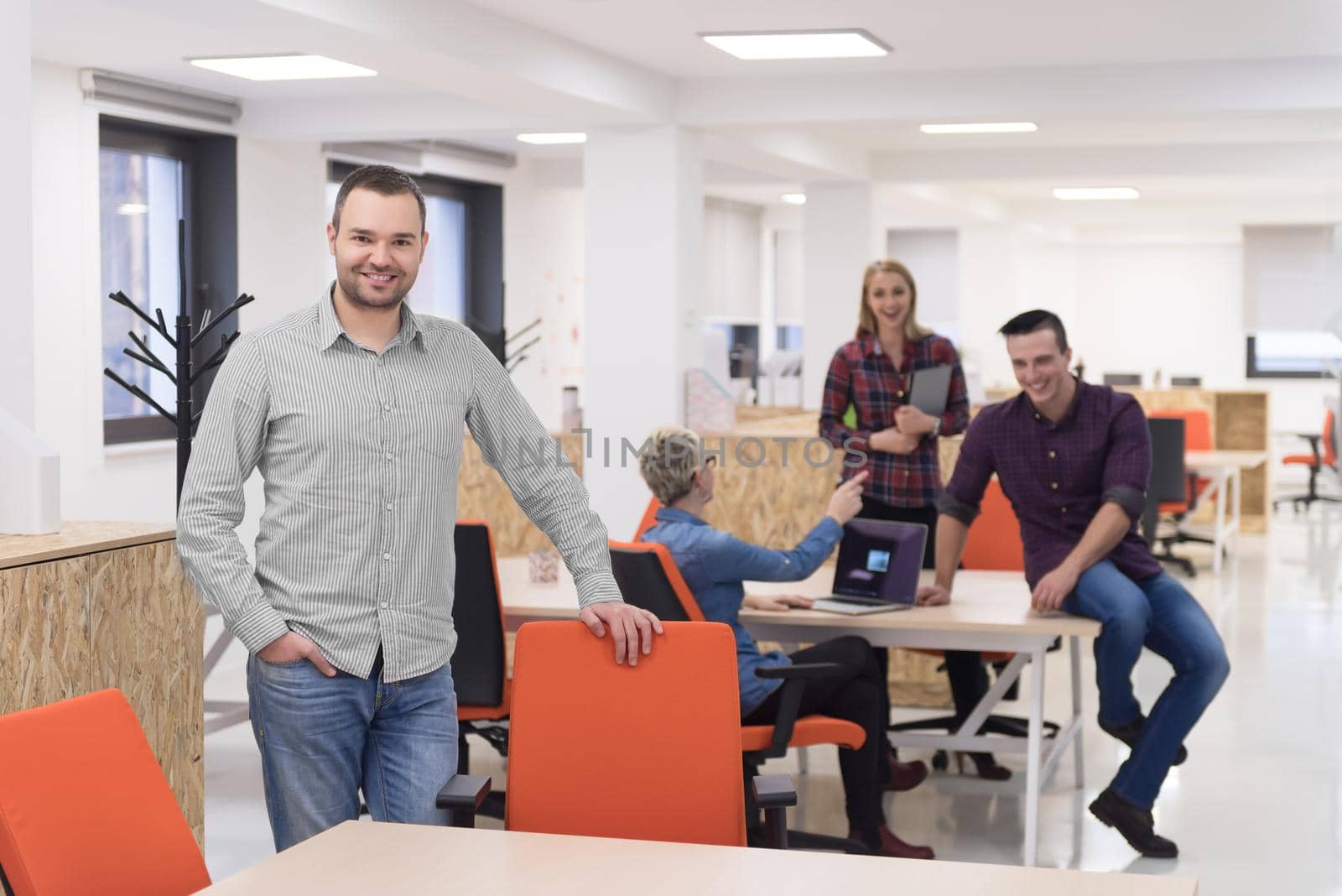 portrait of young businessman in casual clothes at modern  startup business office space,  team of people working together in background