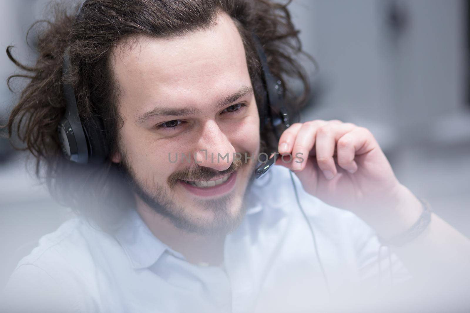 young smiling male call centre operator doing his job with a headset