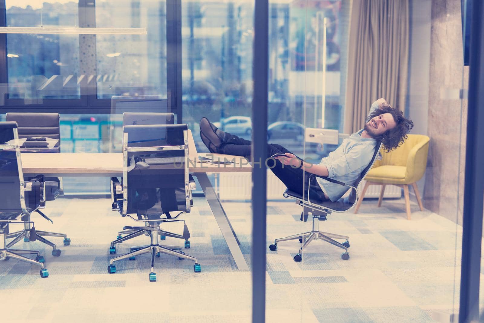 A time for relax. Young tired casual businessman relaxing at the desk in his office