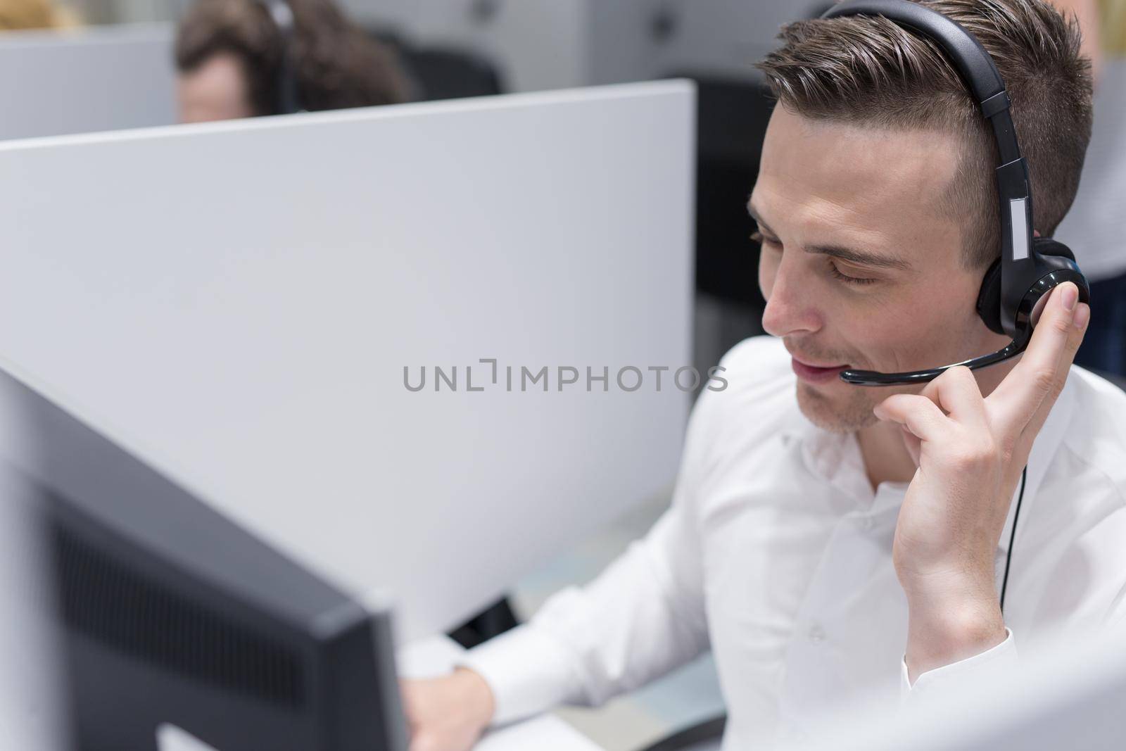 young smiling male call centre operator doing his job with a headset