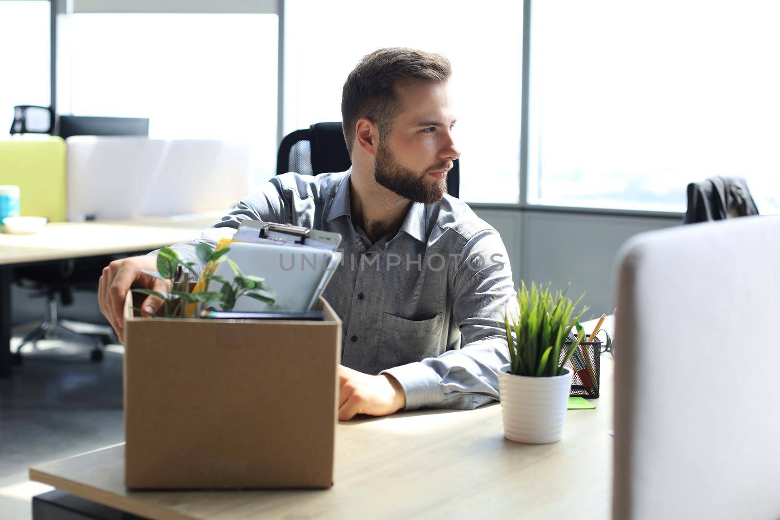 Sad dismissed worker are taking his office supplies with him from office