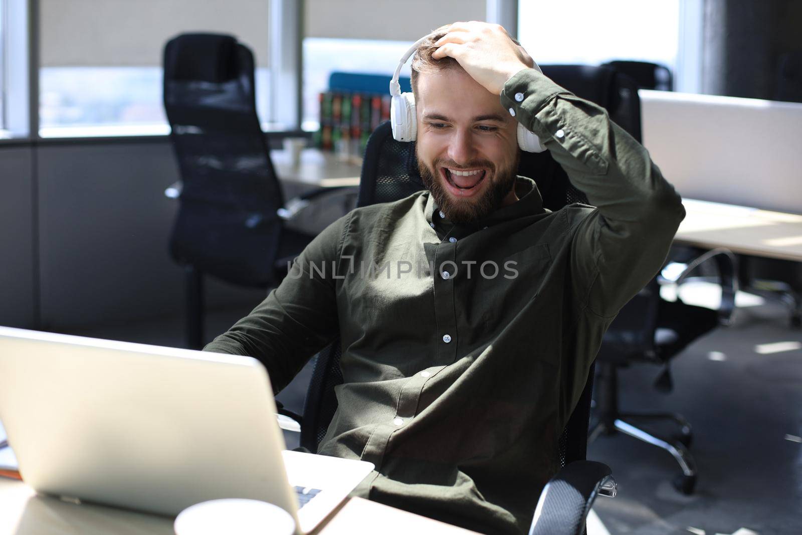 Happy modern business man working using laptop while sitting in the office