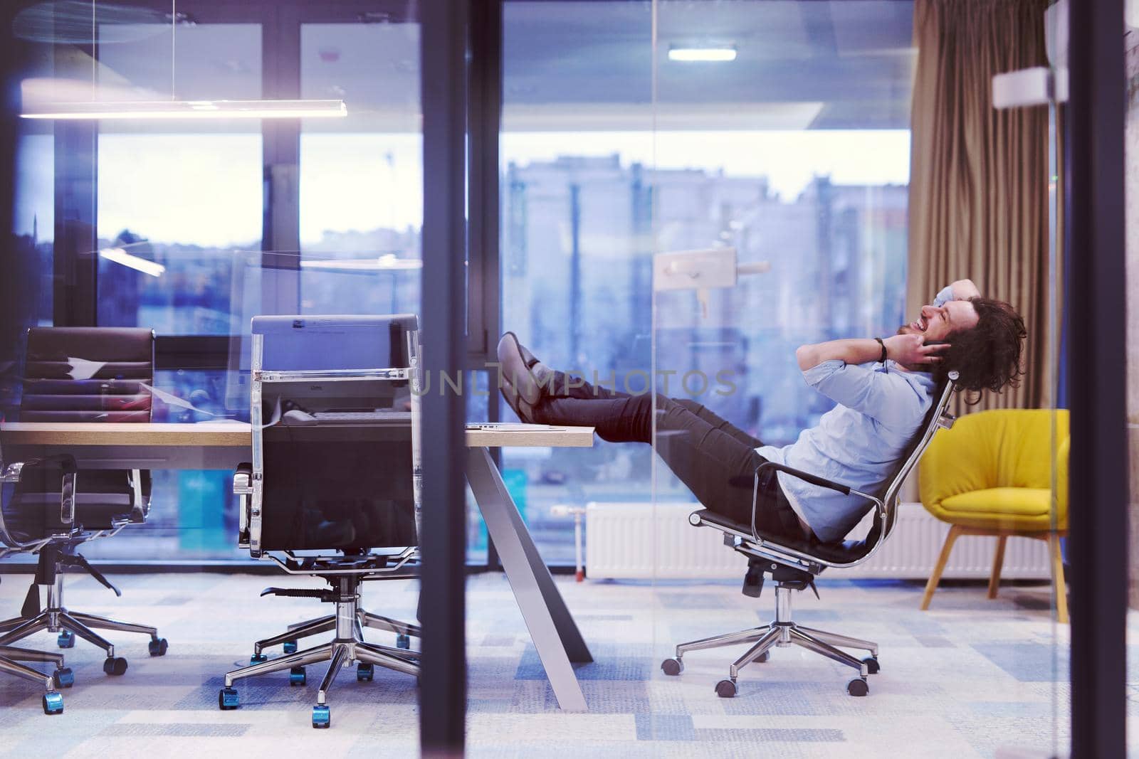 A time for relax. Young tired casual businessman relaxing at the desk in his office